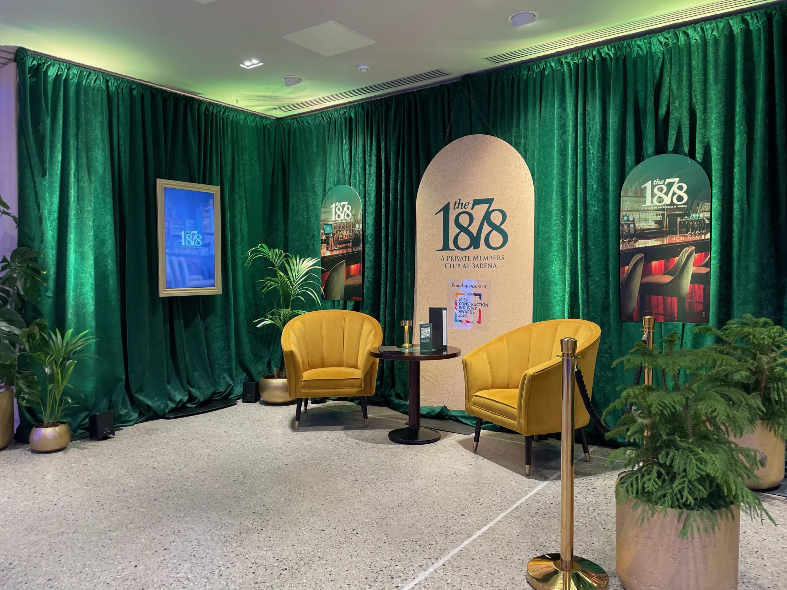Two yellow chairs and a small round table sit before green curtains with