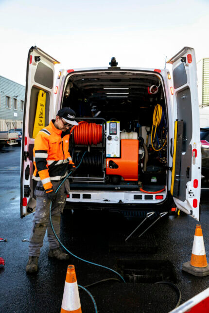 A man working on a van with hydraulic hose fittings attached to it.