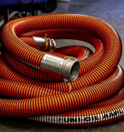         An orange and black hydraulic hose assembly on a floor.