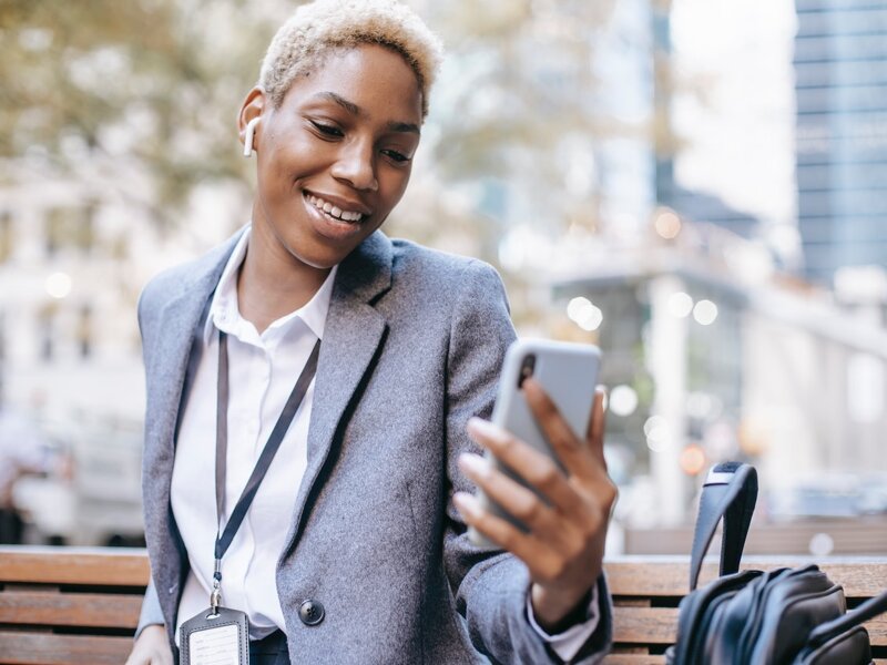 Smiling woman outside looking at smartphone.